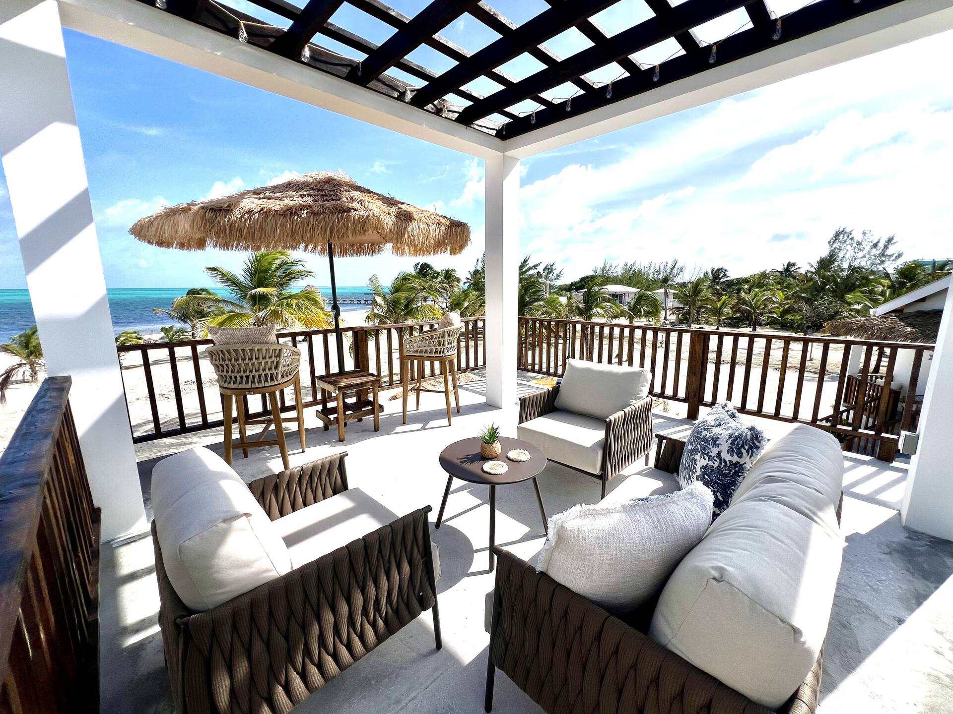 Covered rooftop terrace with cushioned chairs and a thatched umbrella overlooking the Caribbean