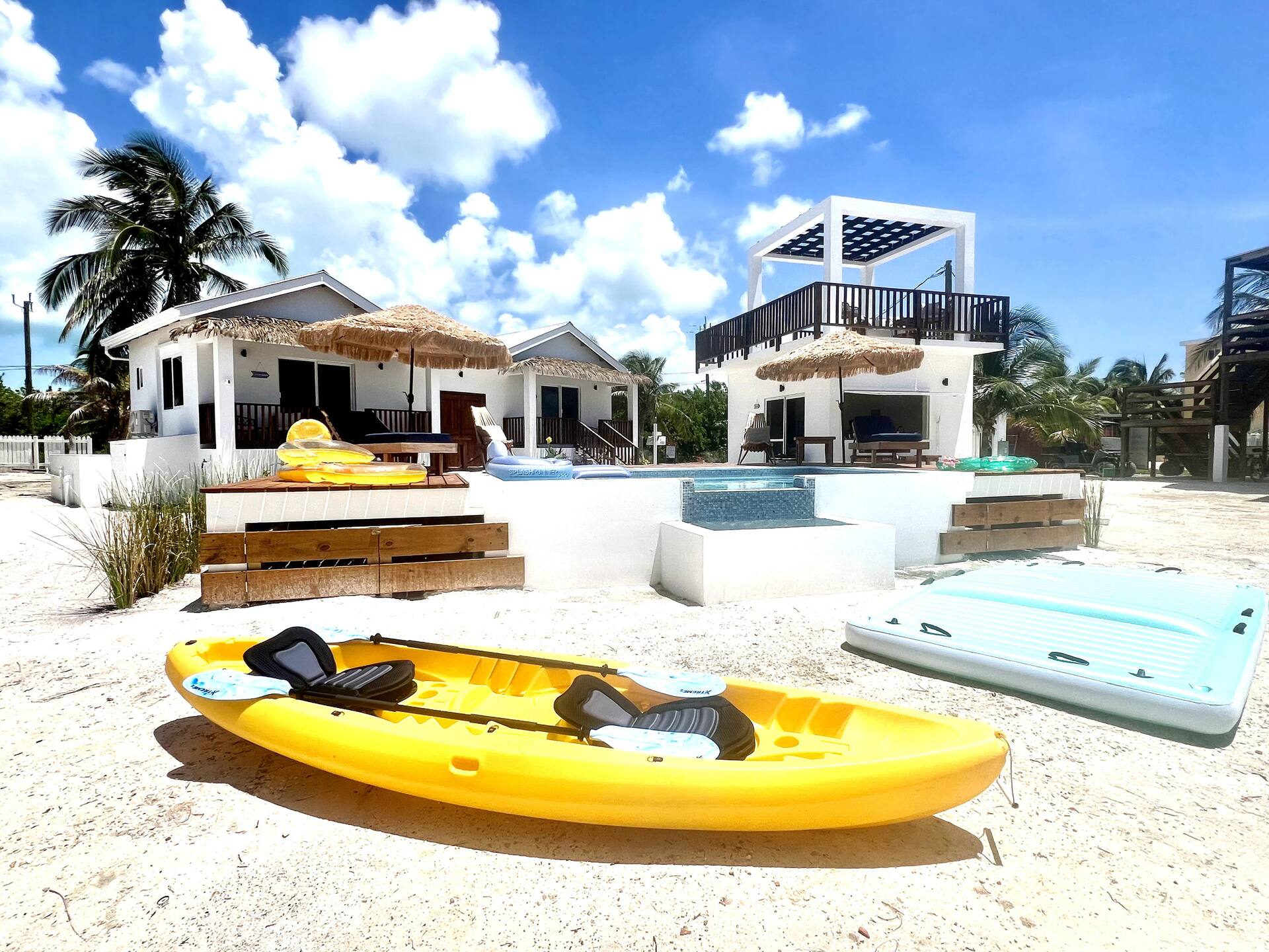 Yellow kayaks on the white sand in front of the casitas and pool