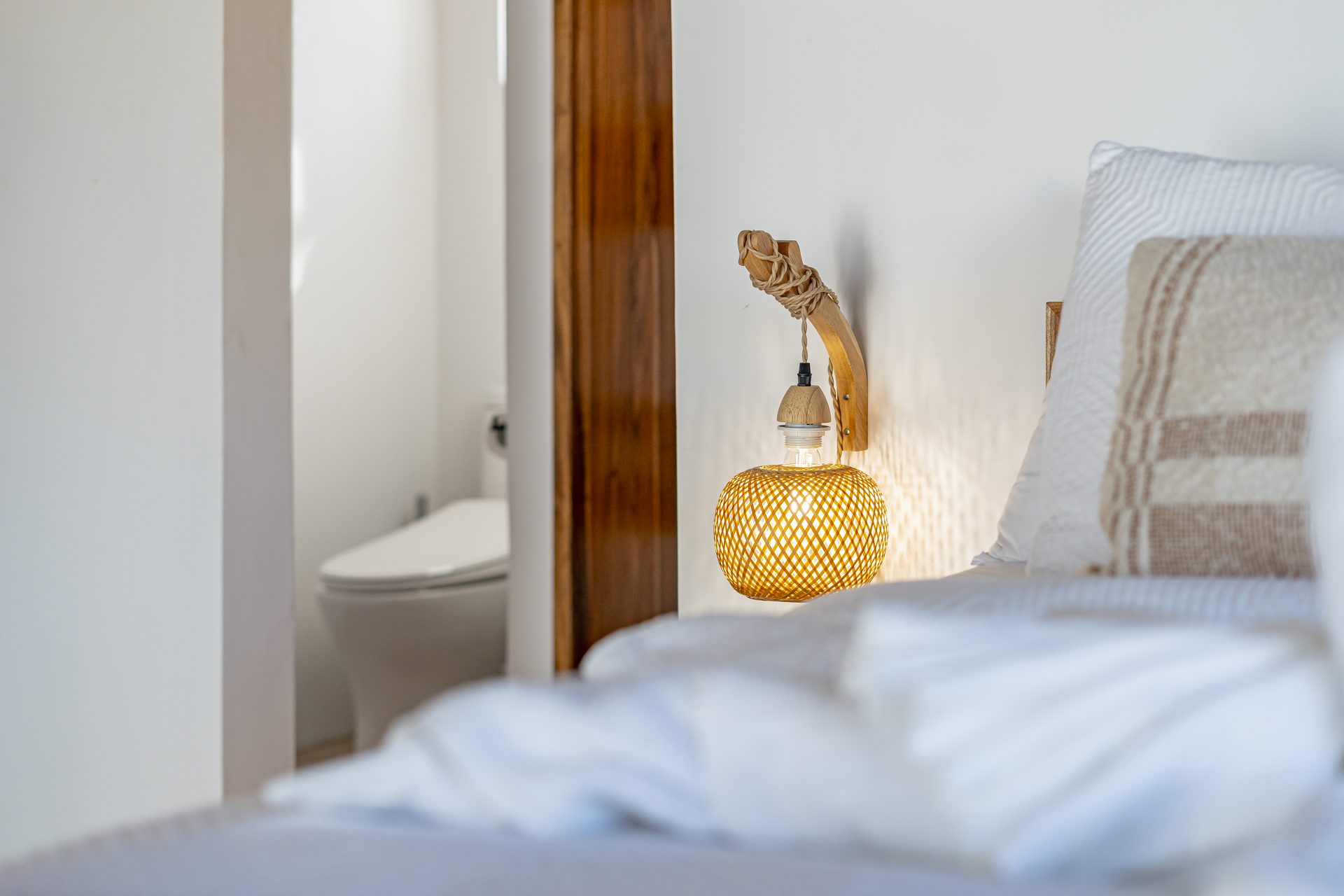 Woven bedside lamp beside the Tarpon Room bed