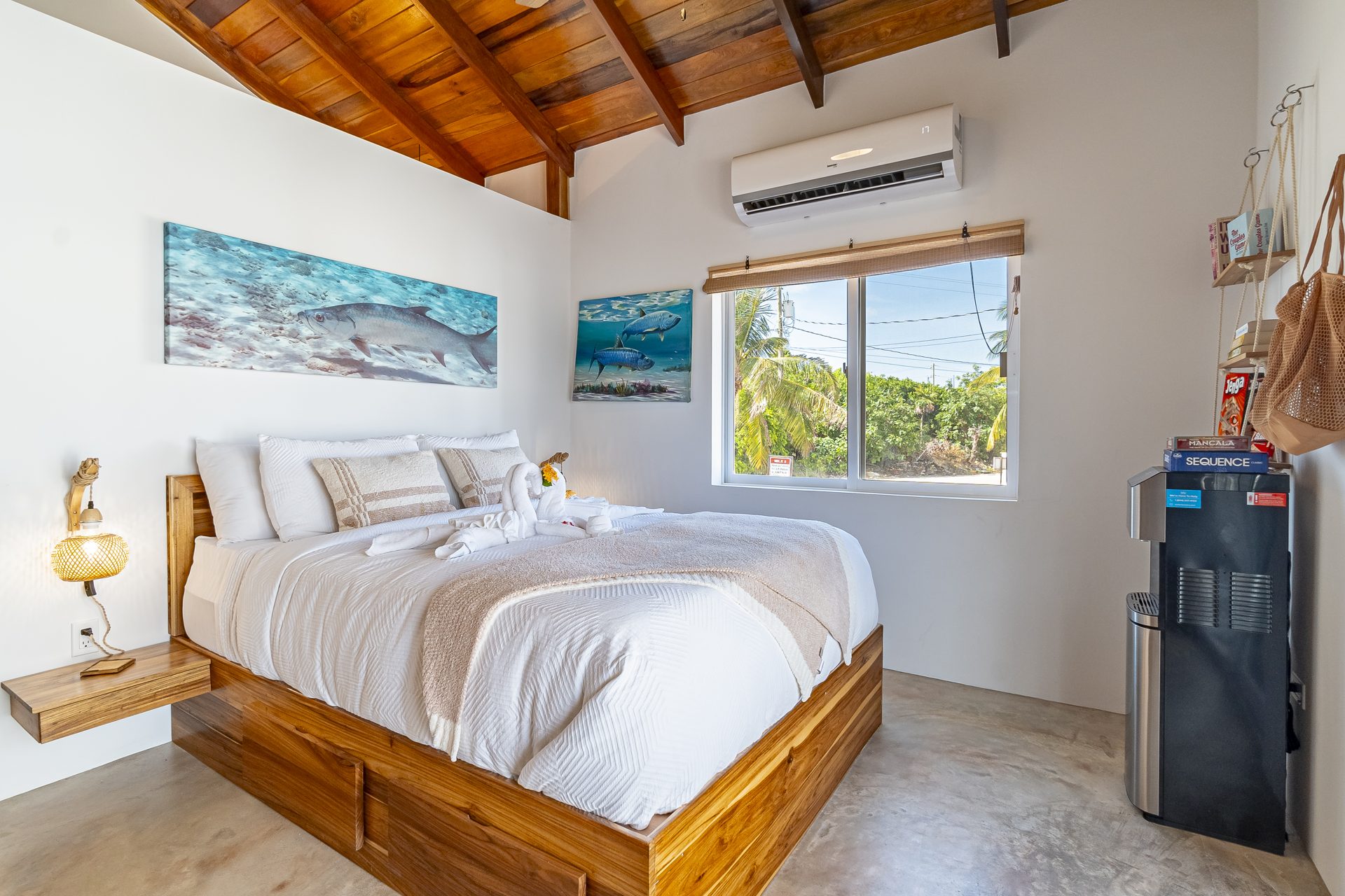 Tarpon Room bed under a vaulted wood ceiling with tarpon artwork